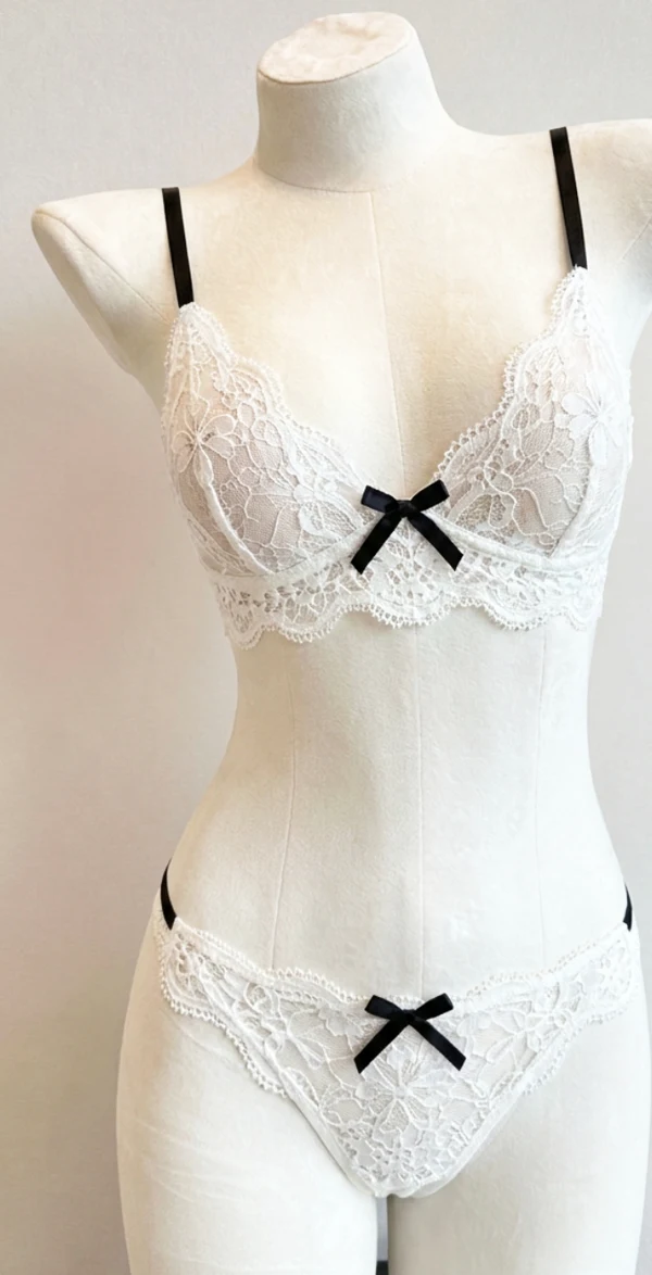 Product reference: white floral lace lingerie with black straps and bows on a mannequin